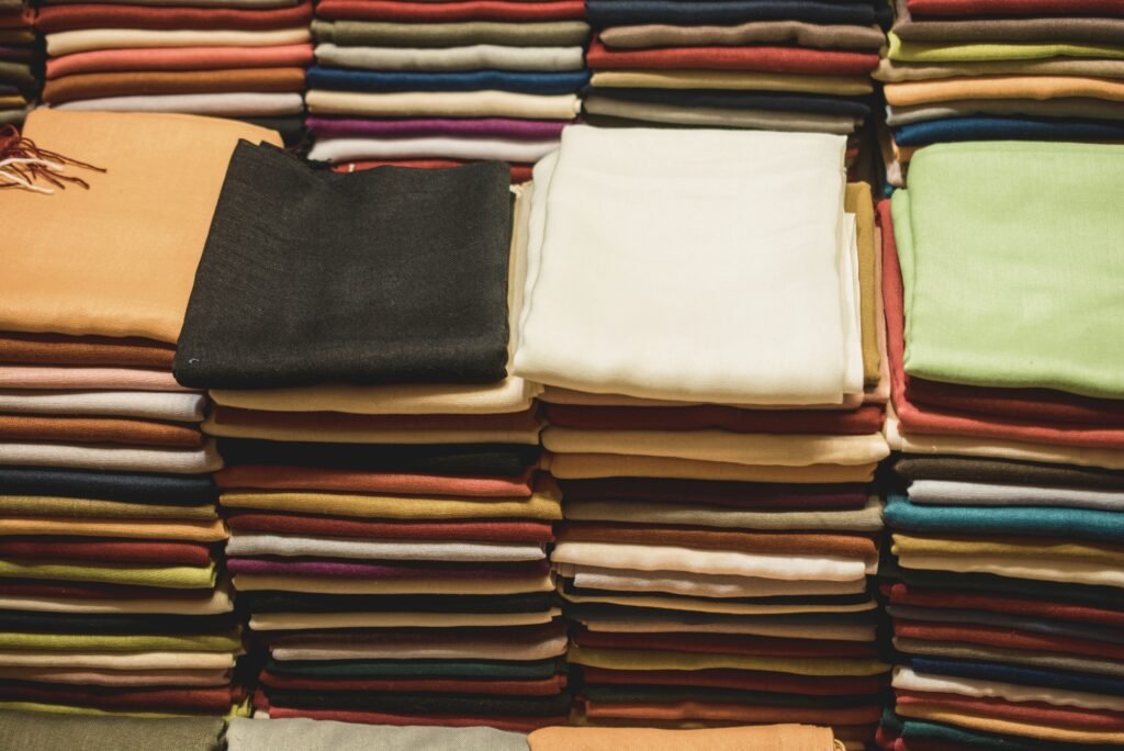 Stacks of folded fabric in a rainbow of colors, arranged neatly in rows.